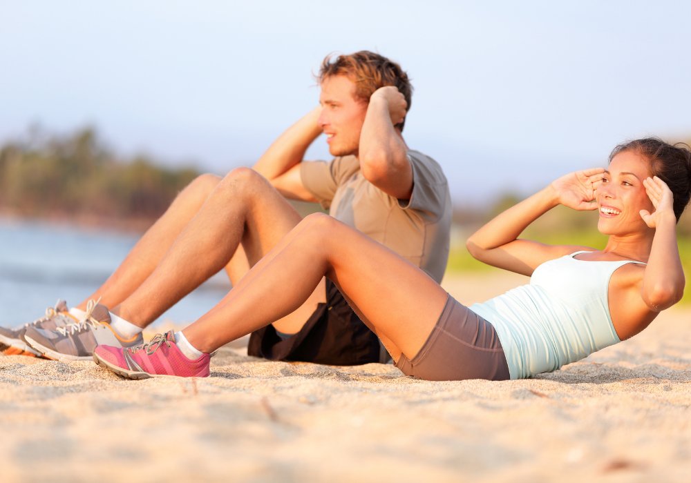 Couple à l'entraînement sur la plage au coucher de soleil, exercices de gainage