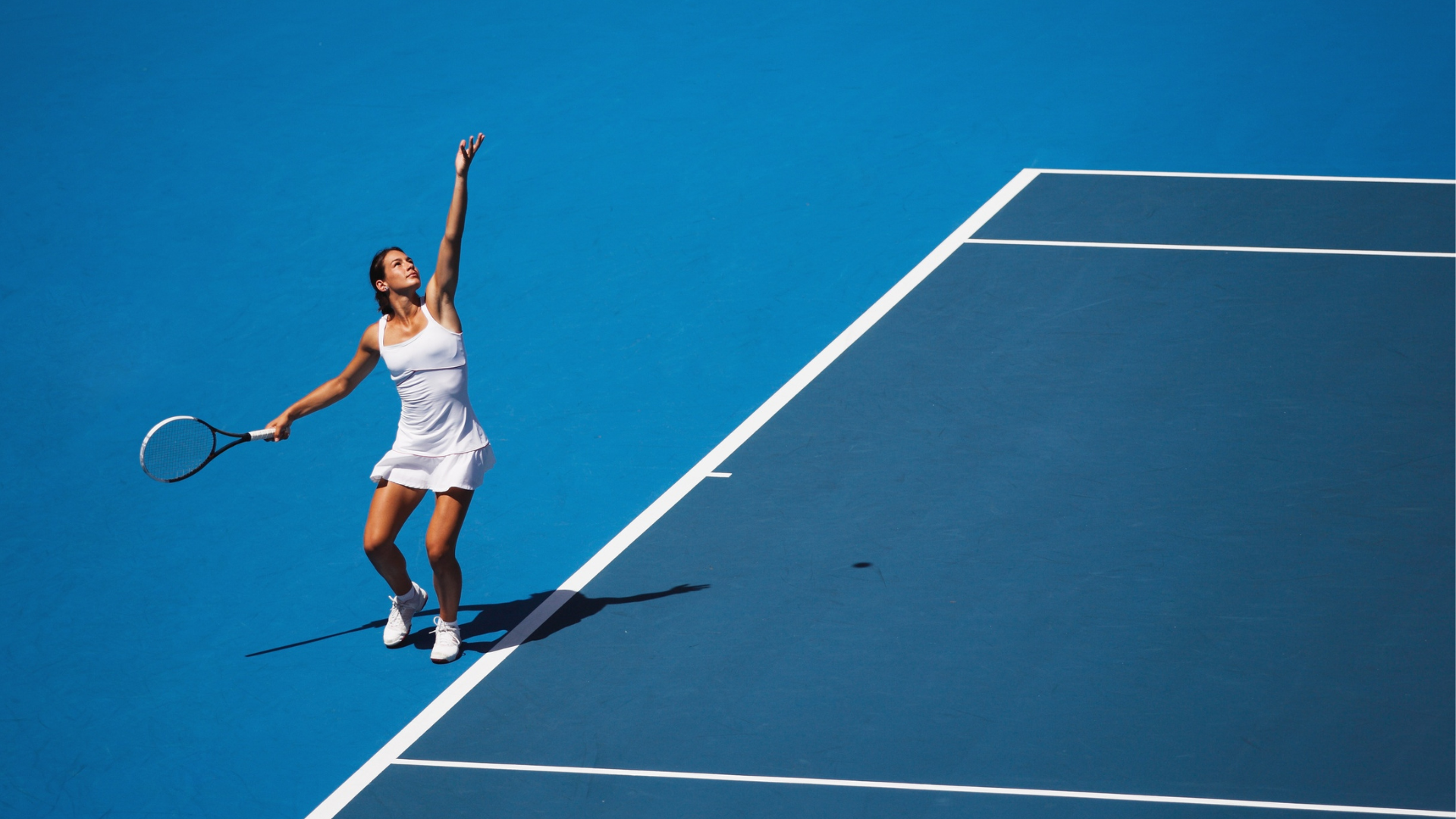 Joueuse de tennis au service sur court bleu